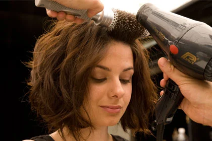 person styling short brown hair with hair dryer