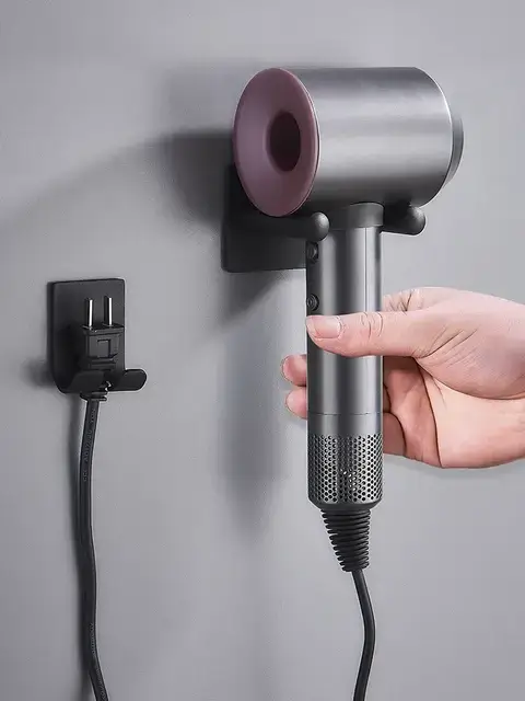 Hand placing modern hair dryer on a magnetic wall mount.