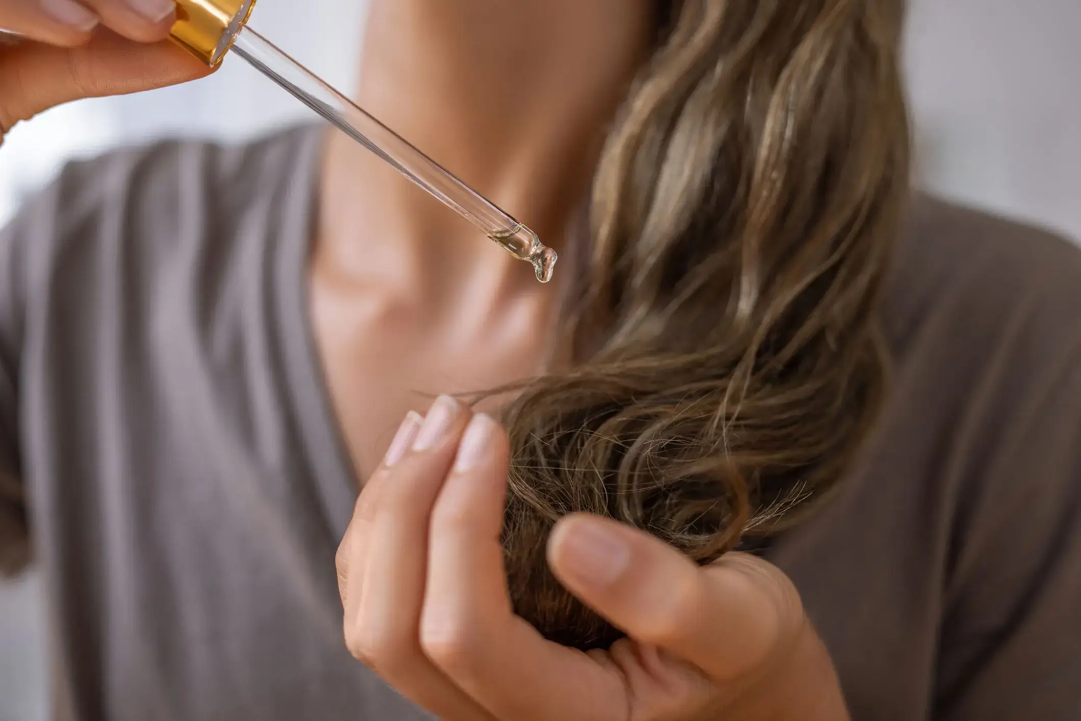 Applying hair oil to ends with a dropper.