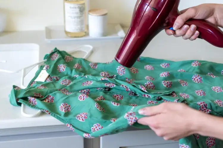 Drying a green shirt with a red hair dryer.