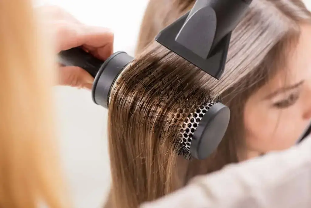 Styling hair with a round brush and blow dryer.