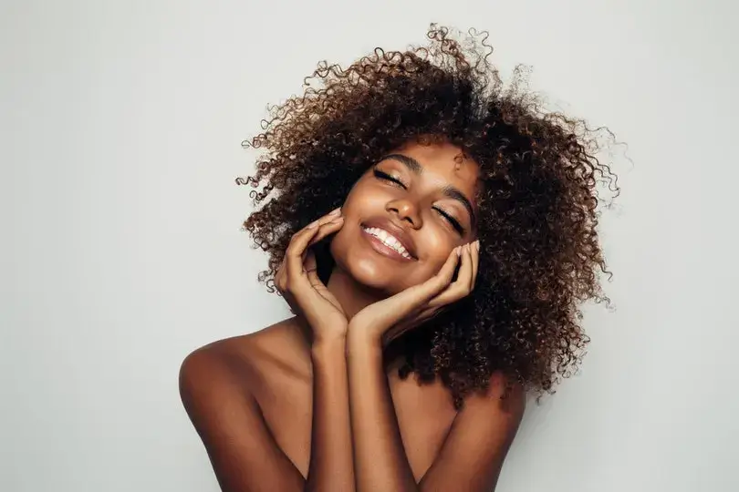 Smiling woman with voluminous natural curly hair.