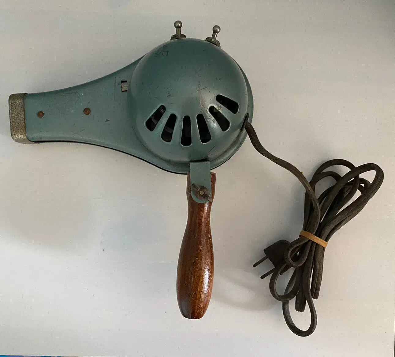 Vintage hair dryer with wooden handle and flexible cord.