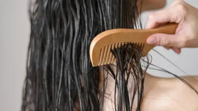 Combing wet hair with a wooden wide-tooth comb.