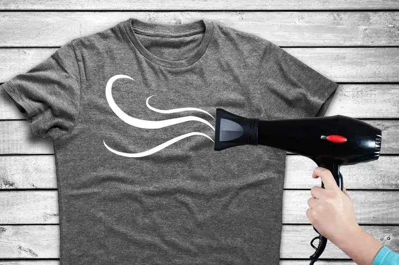 Hairdryer blowing on a t-shirt to dry a paint design.