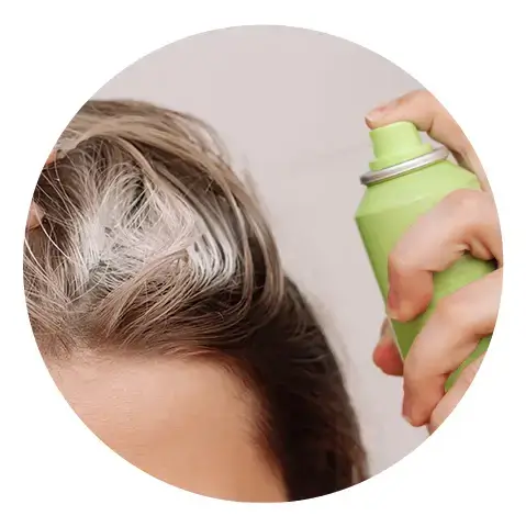 Applying dry shampoo to hair for quick cleansing.