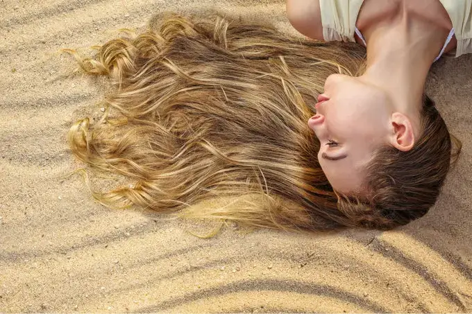 Woman lying on sand, her hair fanned out.