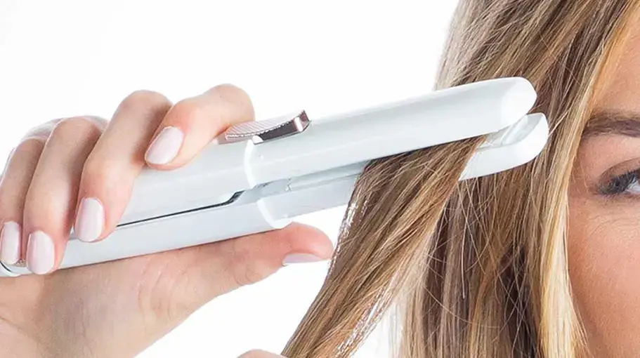 Straightening a section of hair with a white flat iron.