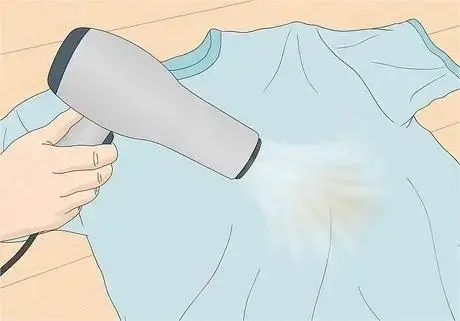 Using a hairdryer to remove wax from a t-shirt.