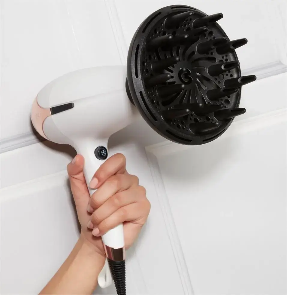 Hand holding a hairdryer with a diffuser attachment.