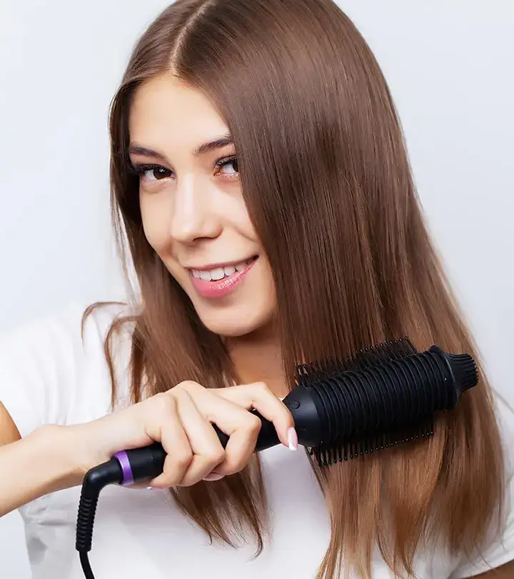 Woman smiling while using a hair straightening brush.