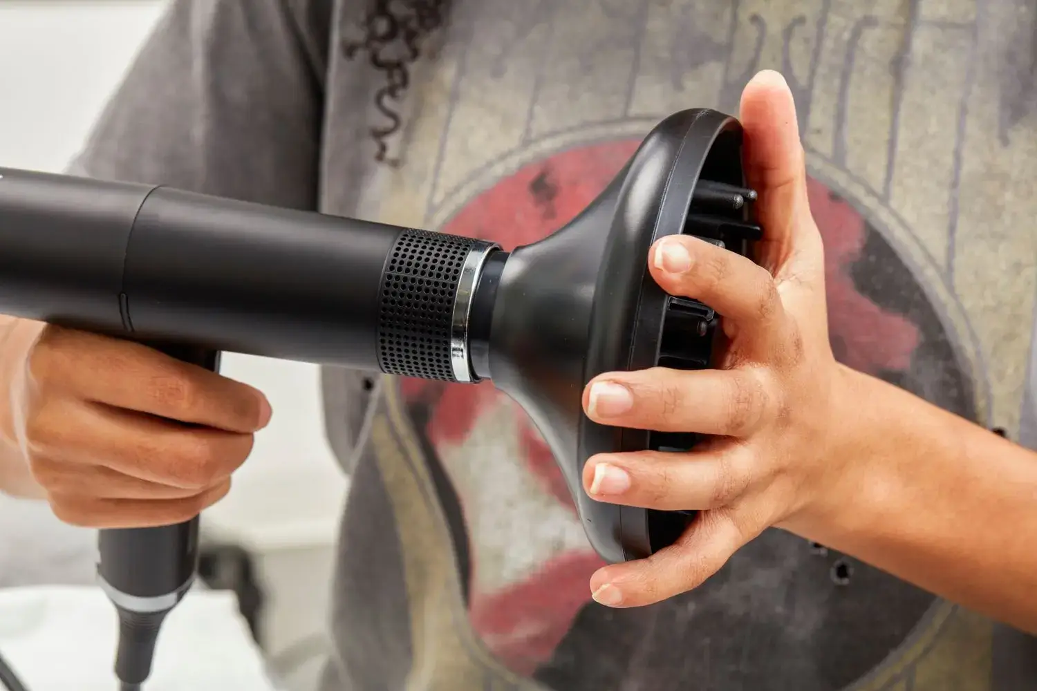 Hand attaching nozzle to a black handheld hair dryer.