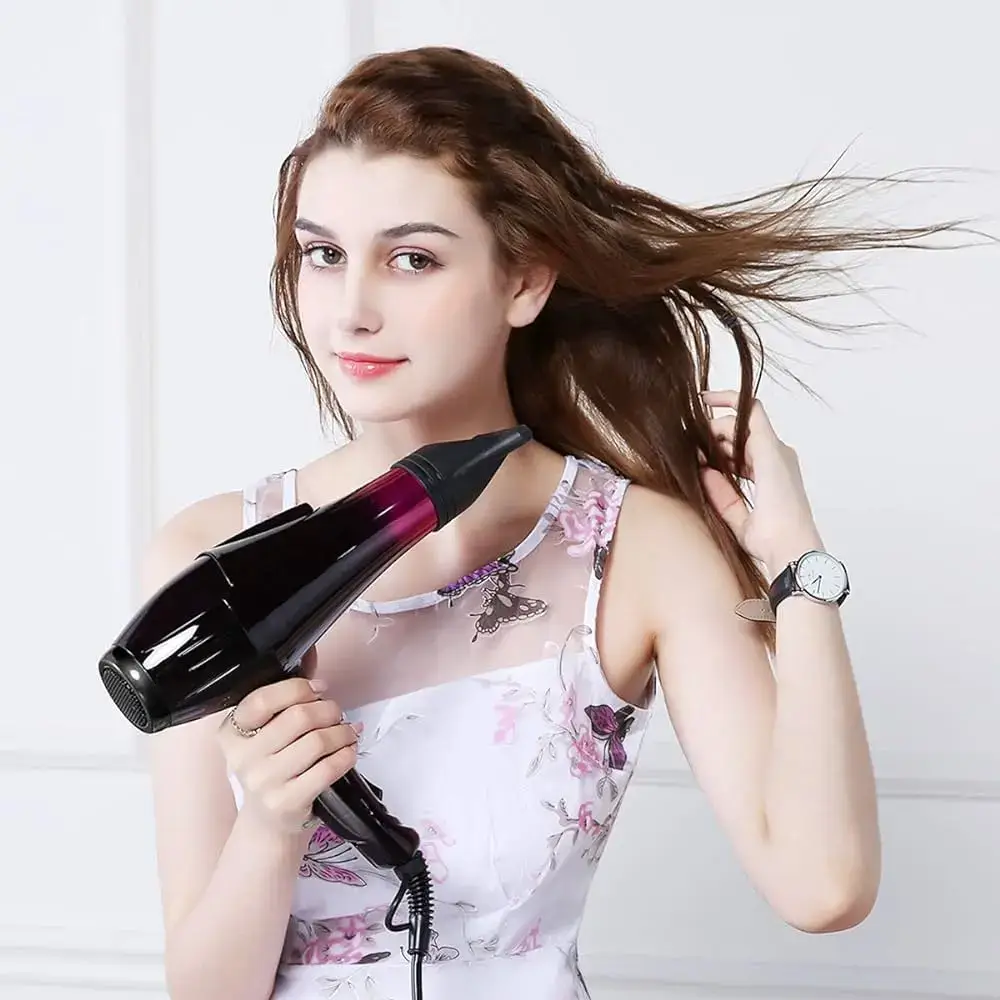 A woman using a hair dryer on her long brown hair.
