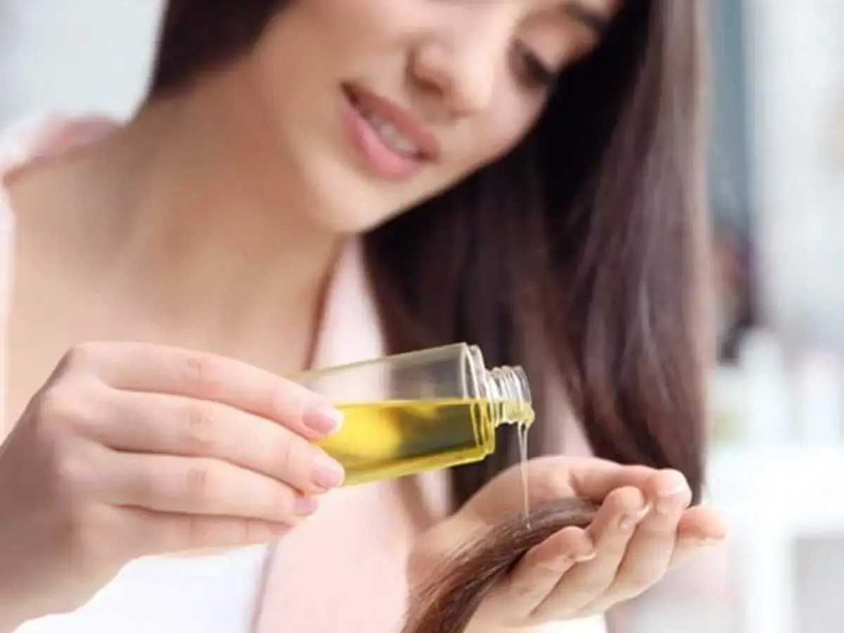 Person applying hair oil to the ends of their hair.