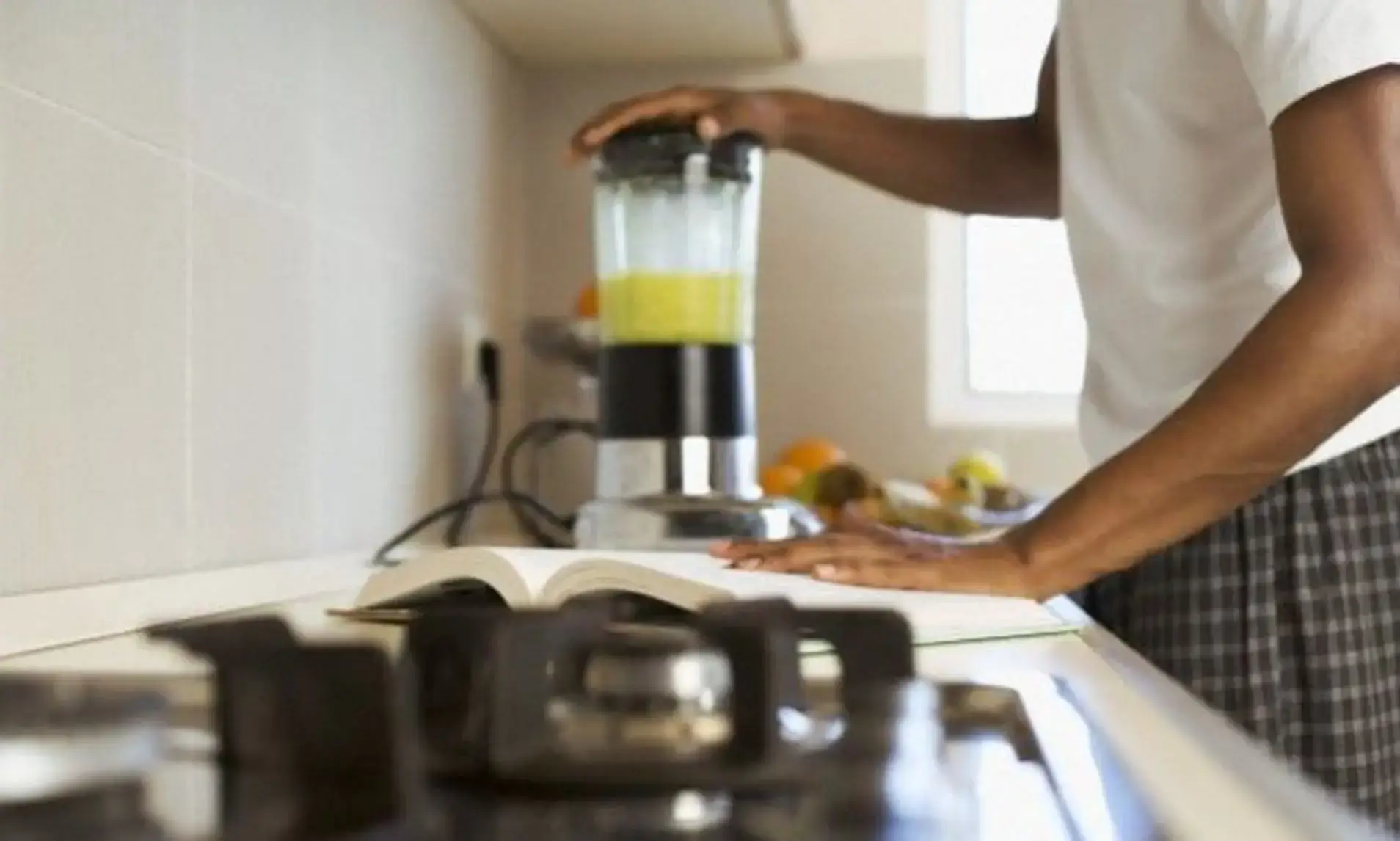 Person using a blender in a kitchen.