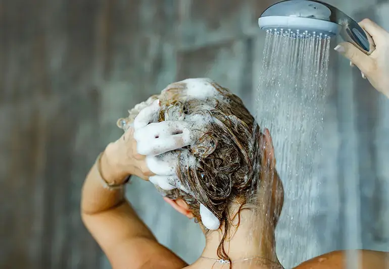 Washing hair with shampoo under a showerhead