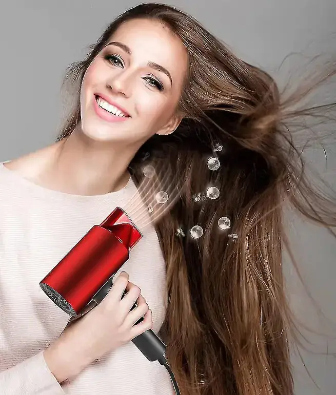 Smiling woman with hair flowing while using a red hairdryer.