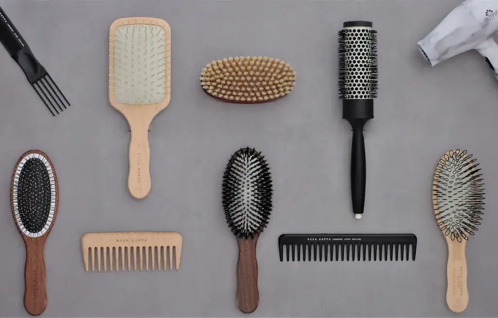 Various hairbrushes and combs laid out on gray background.