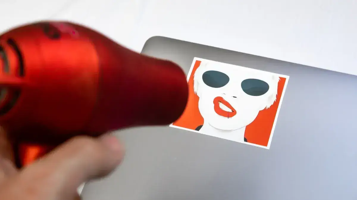Blow dryer removing or applying a graphic vinyl sticker.