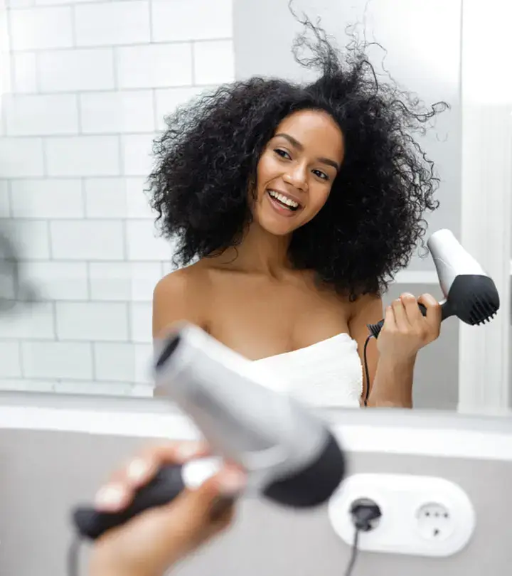 Woman enjoying blow-drying her voluminous curly hair.