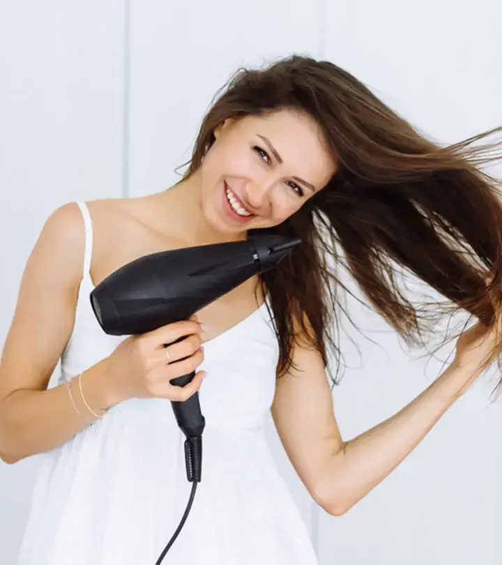 A woman uses a hairdryer to dry her hair evenly