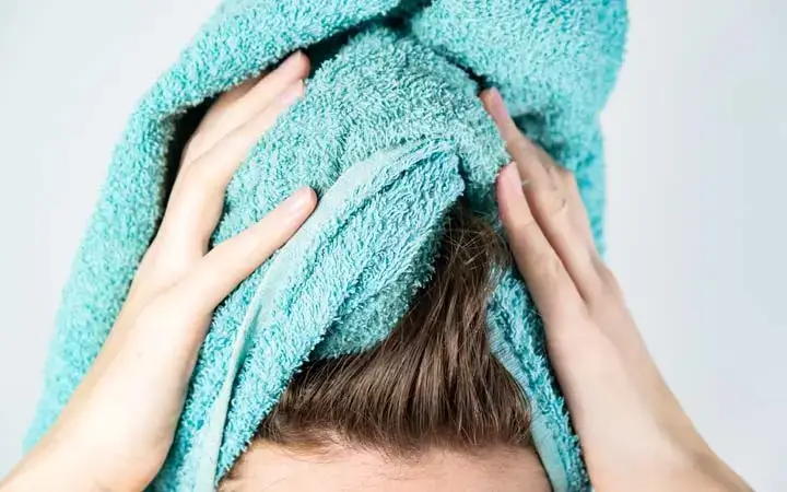 Person drying hair with a turquoise towel.