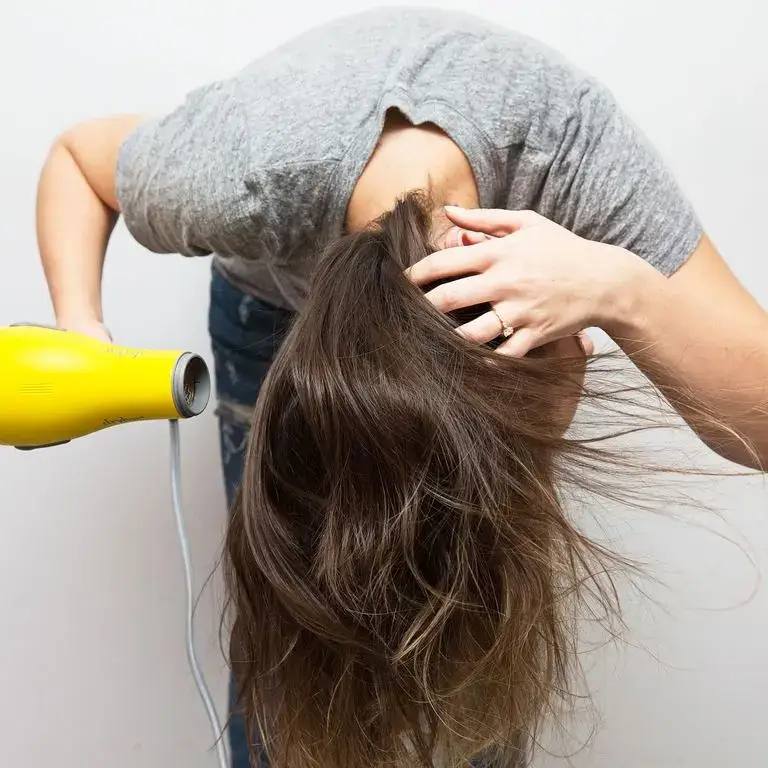 Upside-down hair blow-drying for volume technique demonstration.
