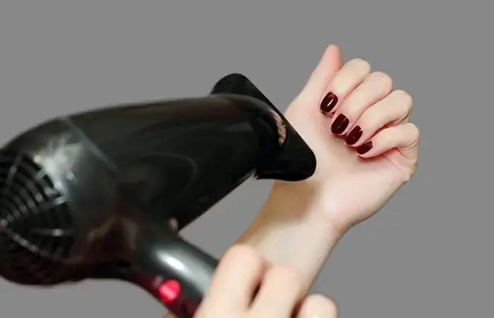 Drying nail polish quickly with a handheld hair dryer.