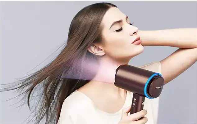 Woman using a hair dryer with intelligent heat technology.